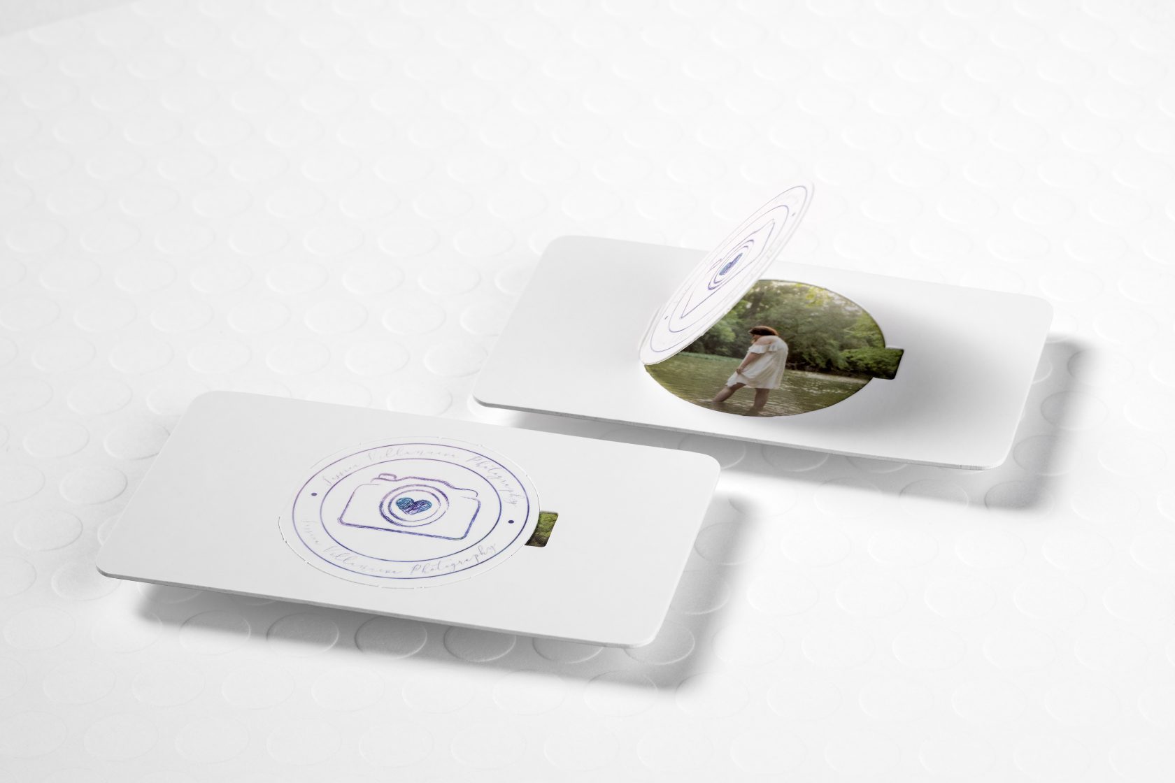 A thick silk lamination card with perforation to show a photograph of a person through the perforated shape of a camera lens.