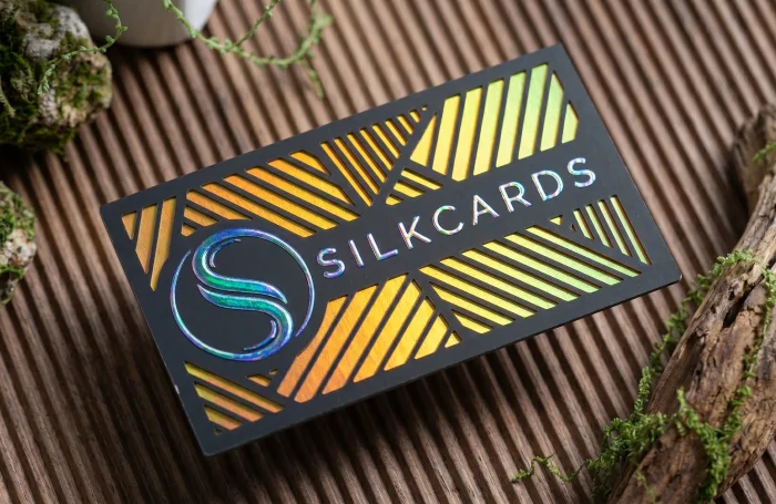 Black business card with holographic gold foil geometric patterns and raised silver foil text.