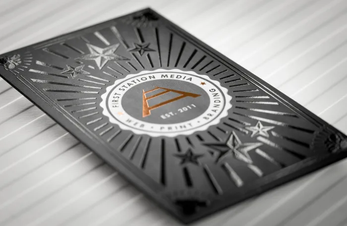 Black business card featuring glossy spot UV rays, stars, and a copper foil logo.