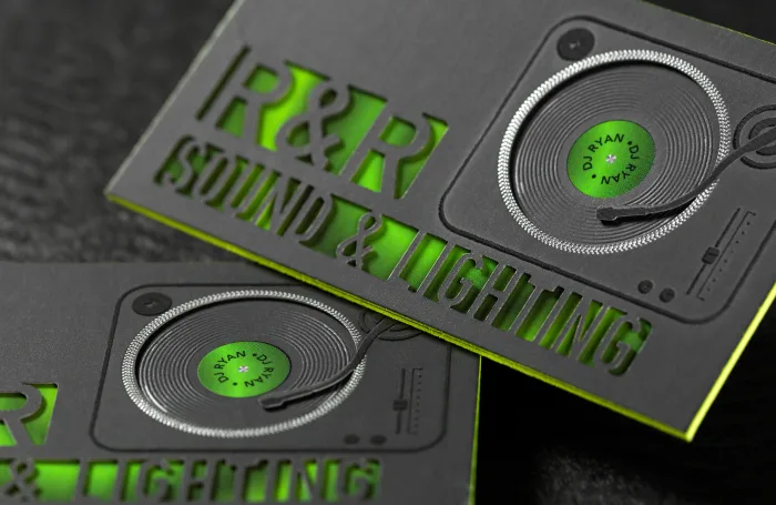 Black suede business cards for R and R Sound and Lighting feature a debossed turntable graphic with a green center label and glowing neon green die cut letters.