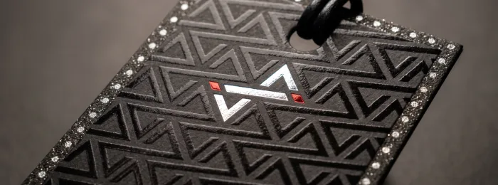 A stack of thick red business cards held in a hand, showing gold foiled edges and a flame emblem on the face.