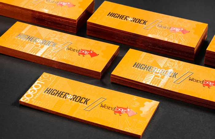 Bright orange silk business cards for Higher Rock Creative Studio feature glossy spot UV patterns and foil accents, displayed in stacked piles.
