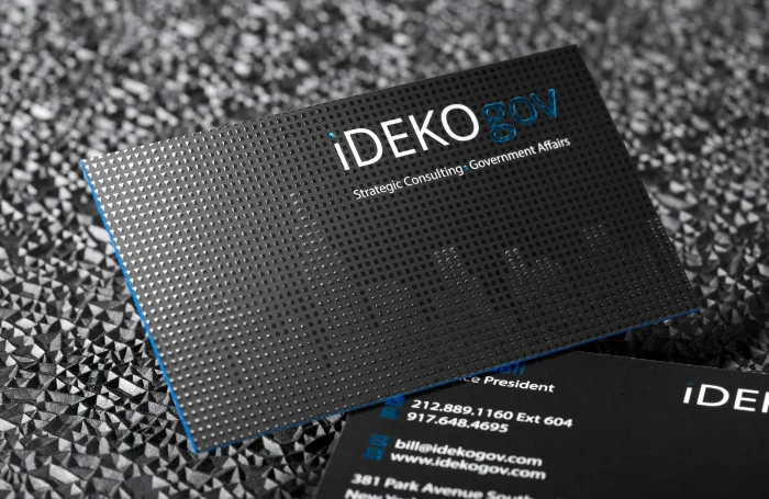 Black business card with raised spot UV texture, blue foil lettering, and blue edges.