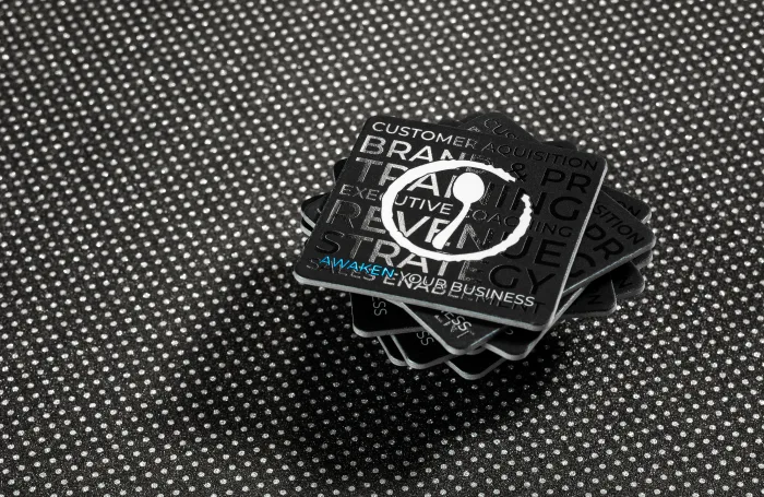 Black business card stack with spot UV finish and blue text.