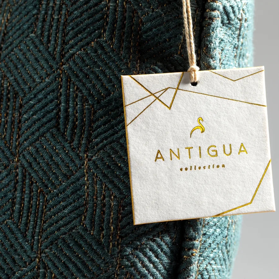 Antigua Collection square cotton hang tag tied with string features gleaming gold foil geometric lines and debossed lettering against a textured white background.